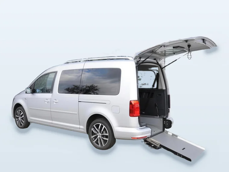 Silberner VW Caddy Maxi mit geöffneter Heckklappe und heruntergeklappter Rollstuhlrampe